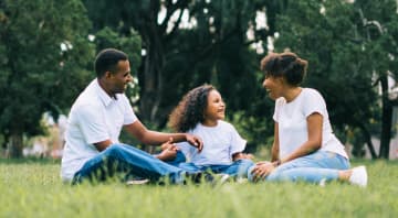 Photo of a family laughing and sitting in the grass