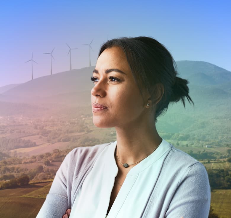 Photo of a woman gazing into the horizon, with a wind farm in the background